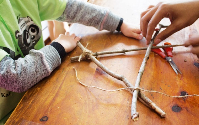 Child and Adult weaving together natural loose parts